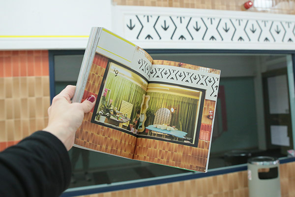 Arm hold book infront of some lovely 1970s tiling.