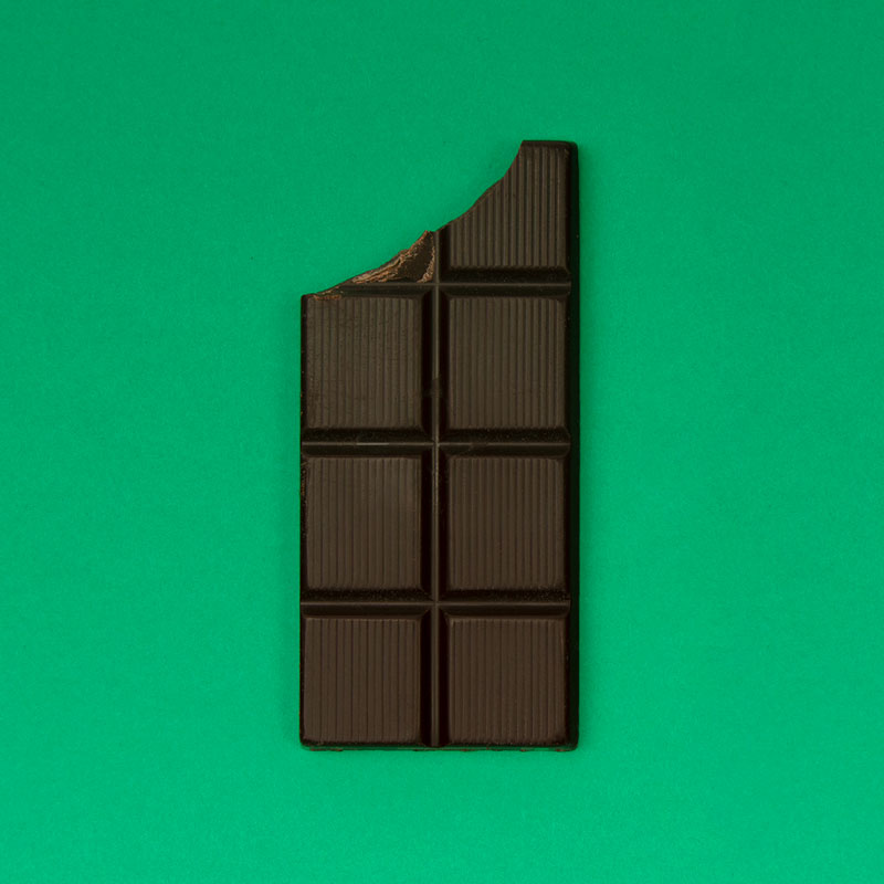 Dark chocolate bar on a green background.