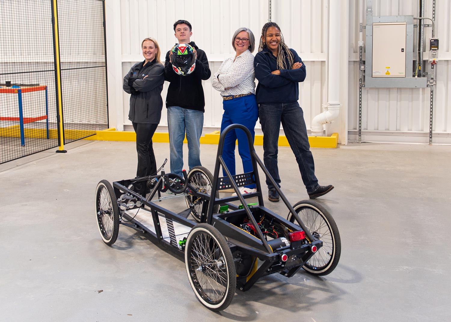 A team of 4 pose behind their electric go-kart.